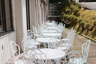 食堂横にある白い円卓と椅子が並べられたテラス席の写真